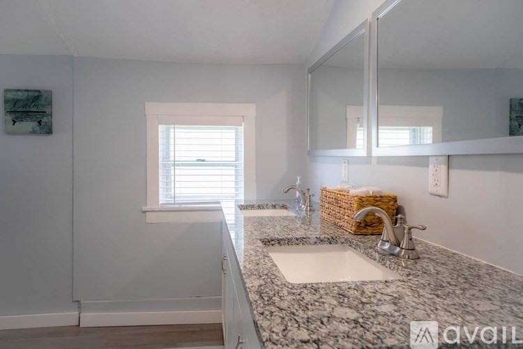 A bathroom with a marble countertop and a window with blinds.