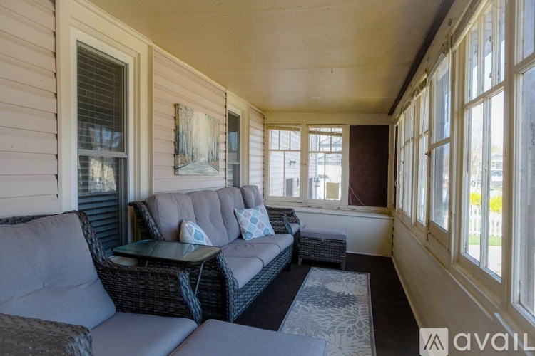 A sunroom with a couch, table, and a painting on the wall.