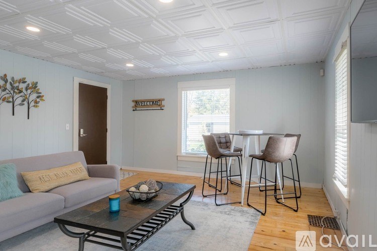 A living room with a grey couch, a coffee table, and a dining table with chairs.