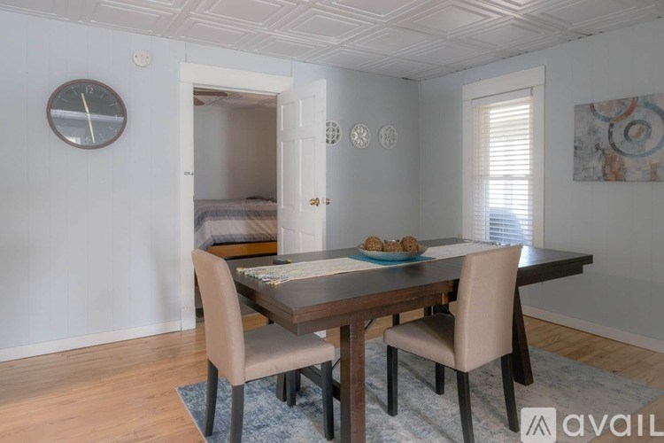 A dining room with a table set for two and a clock on the wall.