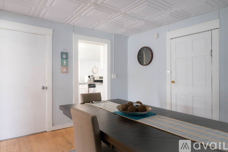 A dining room with a table and chairs and a clock on the wall.