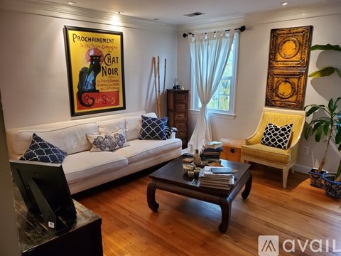 A living room with a white couch, a coffee table, a chair, and a painting on the wall.