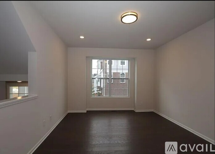 A spacious room with a large window and wooden flooring.