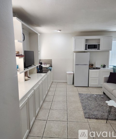A kitchen with white cabinets and a refrigerator.