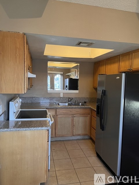 A kitchen with wooden cabinets and a black refrigerator.