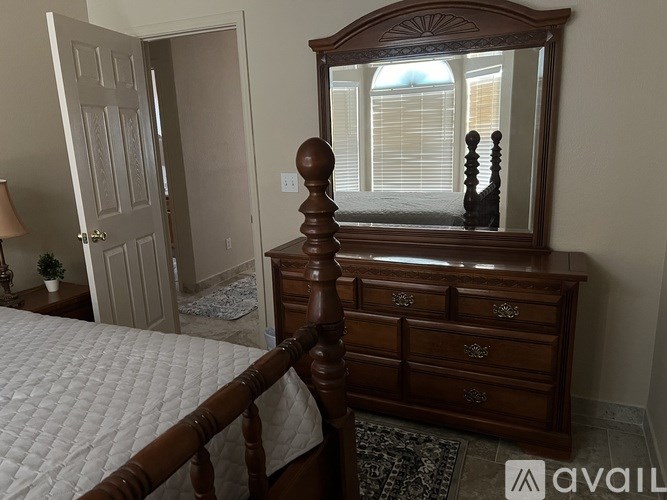 A bedroom with a bed, dresser, and mirror.