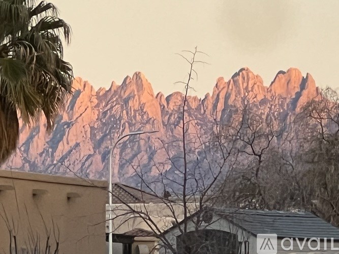 A mountain range is seen in the background with a house and trees in the foreground.