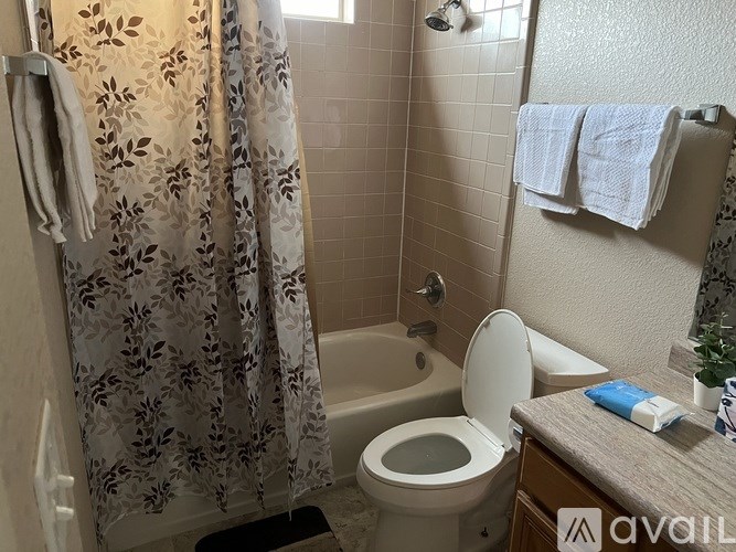 A bathroom with a toilet, a shower curtain, and towels hanging on the wall.