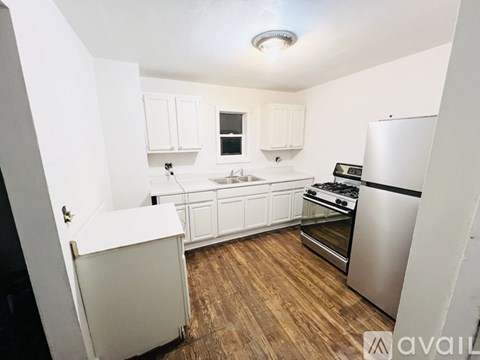 A kitchen with white cabinets and a wooden floor.