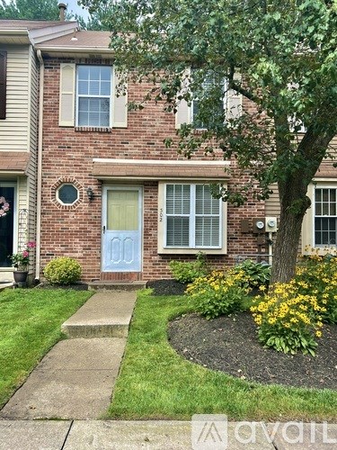 A brick house with a blue door and a tree in front.