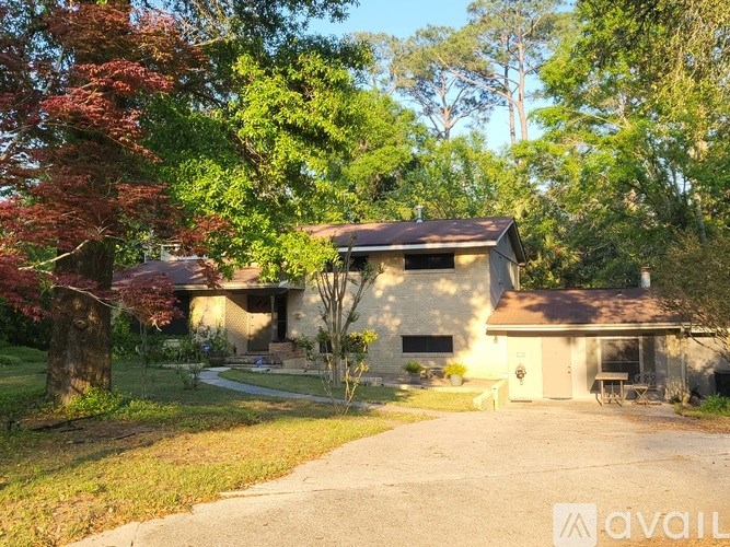 A house with a driveway and trees in front of it.
