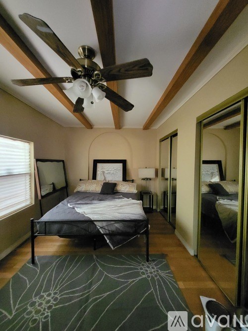 A bedroom with a bed, a ceiling fan, and a rug.