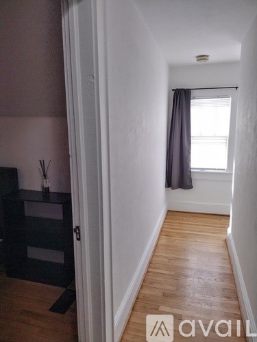 A hallway with a window and a black cabinet.