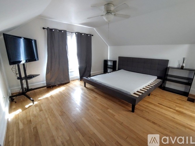 A bedroom with a bed, a television, and a ceiling fan.