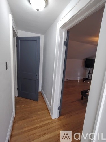 A hallway with a dark door and a light wooden floor.