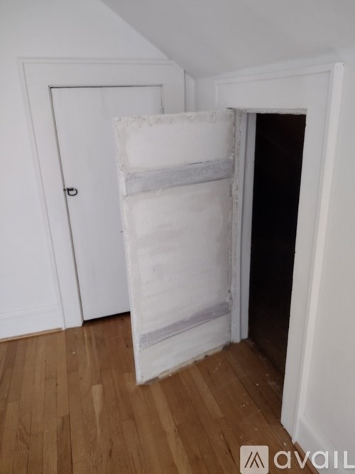 A room with a white door and a white wall with a white mattress on the floor.