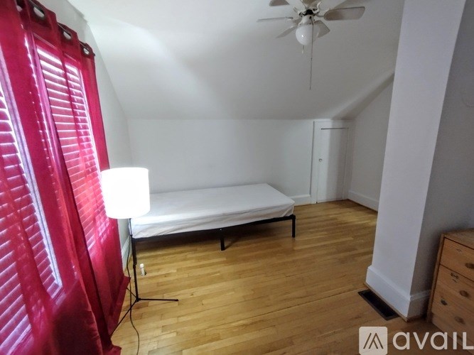 A room with a bed, a fan, and a wooden floor.