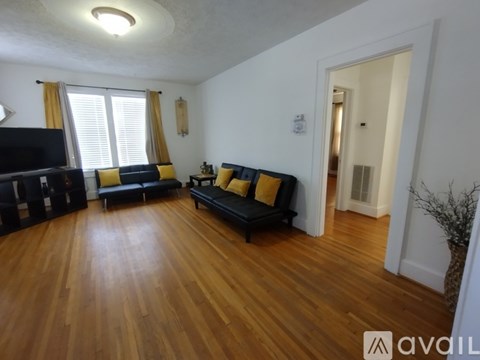 A living room with a black couch and a wooden floor.