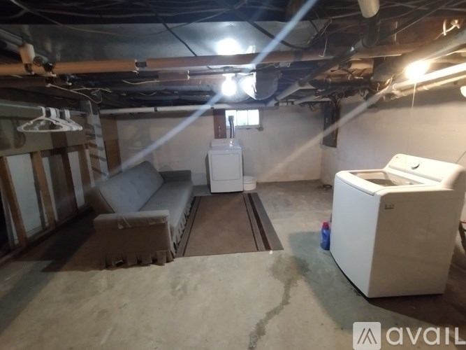 A room with a white refrigerator and a window with blinds.