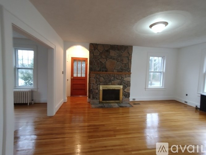 A living room with a stone fireplace and wood floors.