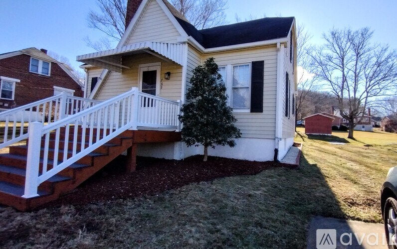 A house with a white fence and a small tree in the front yard.