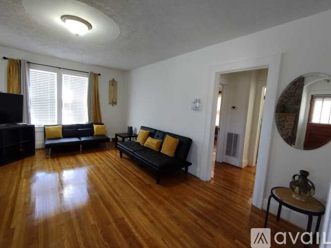A living room with a black couch and yellow pillows.