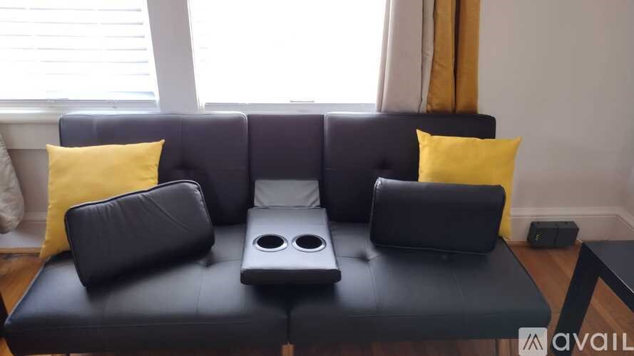 A black sofa with a built-in entertainment center and two yellow pillows.