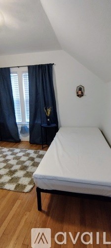 A white mattress is on a wooden frame in a room with a window.