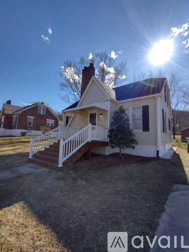 A house with a white fence and a small tree in front of it.