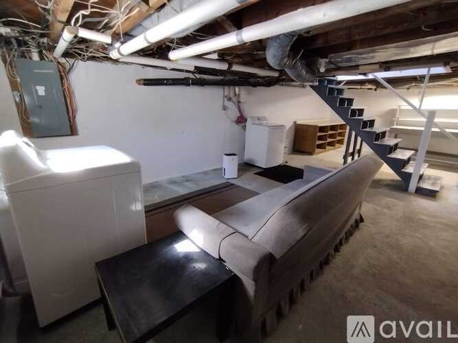 A room with a washing machine, dryer, and a staircase.