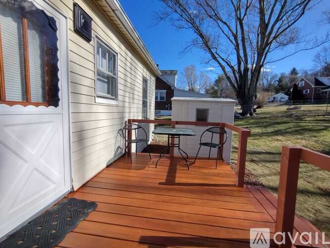 A small white house with a wooden deck and a small table and chairs.