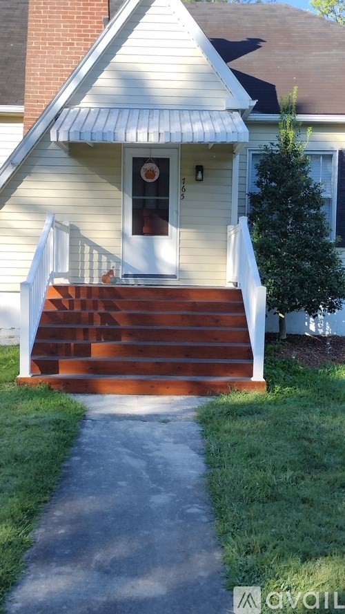 A house with a white front porch and a brown staircase.