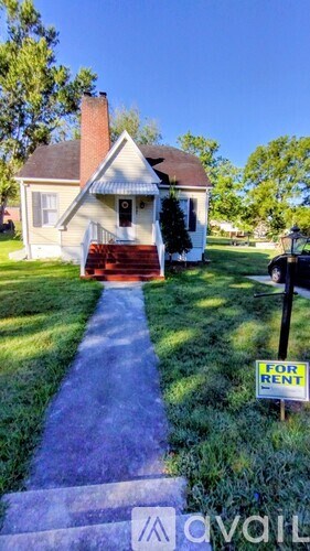 A house is for rent and is located in a grassy area.