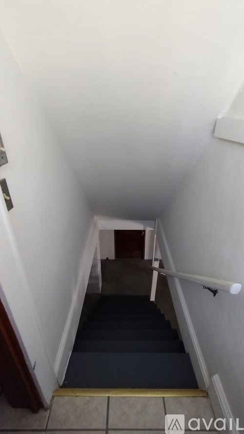 A stairway with a blue carpeted runner and white walls.