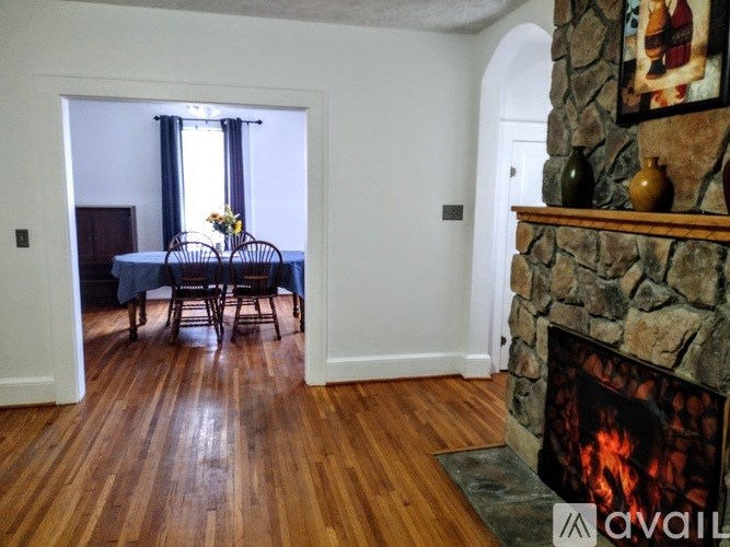 A room with a stone fireplace and a dining table with chairs.
