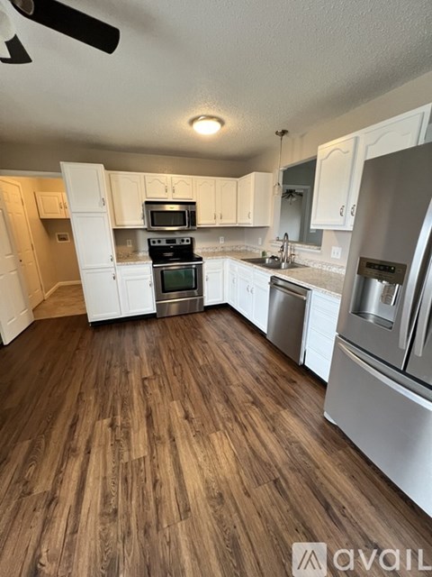 A kitchen with white cabinets and a wooden floor.