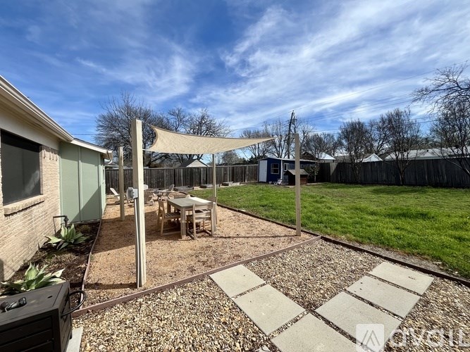A backyard with a patio and a table under a canopy.