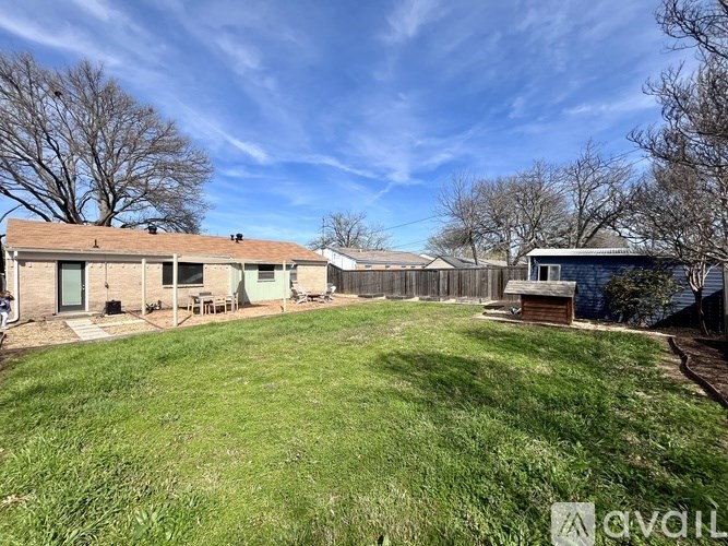 A backyard with a fence and a house in the background.