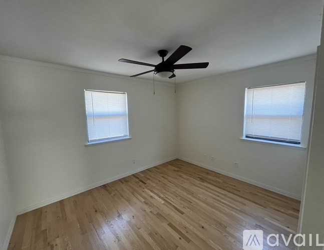 A room with a ceiling fan and two windows.