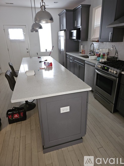 A kitchen with a white island and grey cabinets.