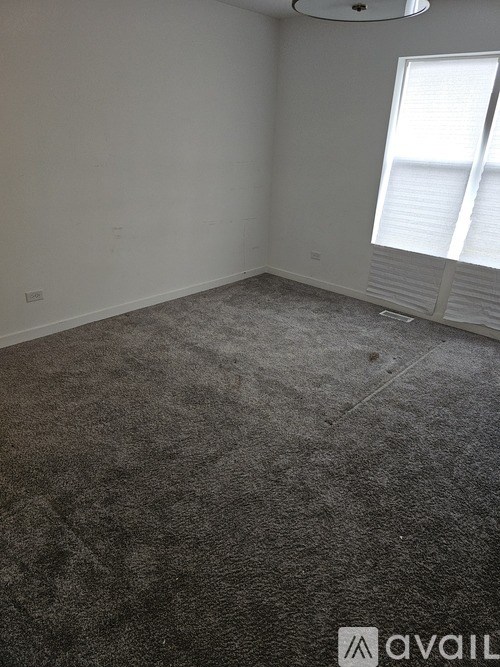 A room with a carpeted floor and a window with blinds.