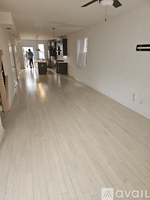 A spacious room with a fan and wooden flooring.