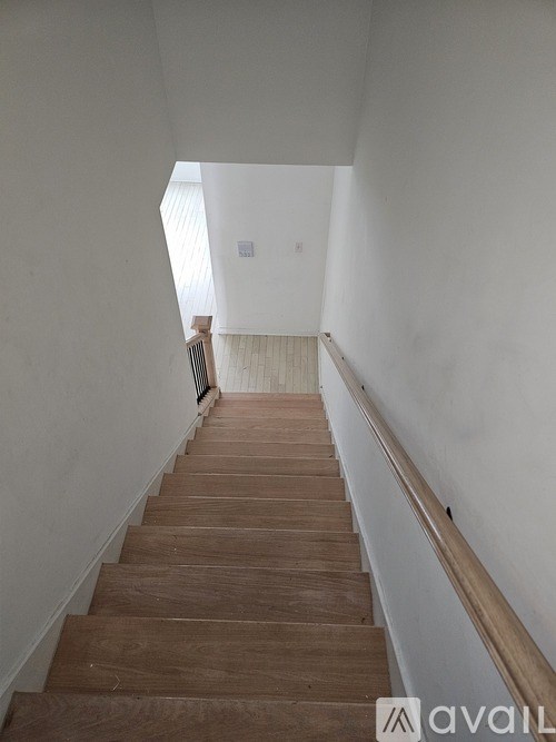 A long flight of wooden stairs leads to a bright window.