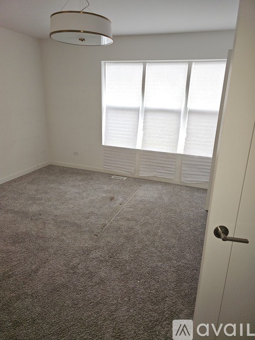 A room with a carpeted floor and a door leading to a window with blinds.