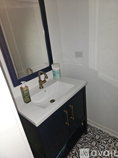 A white sink with a green bottle on it.