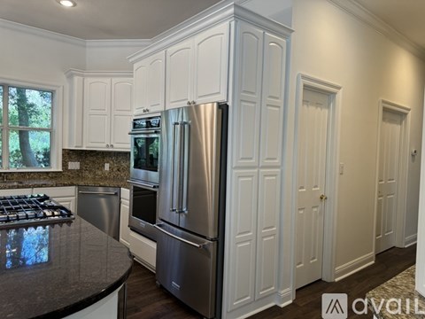 A modern kitchen with white cabinets and stainless steel appliances.