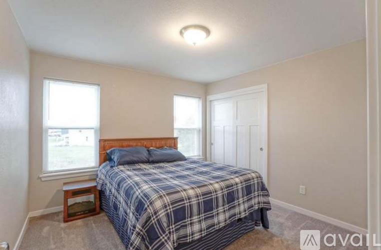 A bedroom with a bed, nightstand, and window.