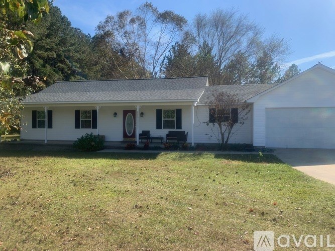 A white house with a grey roof and a red door.