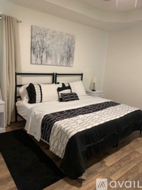 A bedroom with a large bed and a painting on the wall.