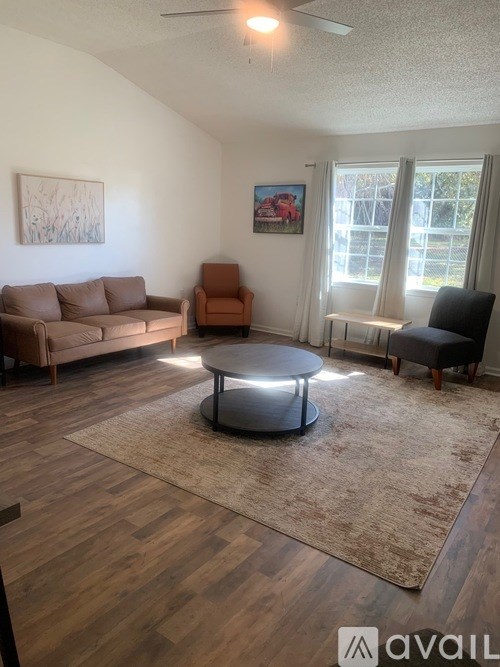 A living room with a brown couch, a grey coffee table, and a rug.